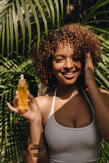Model holding Mimane Glow Growth and Strengthen Hair Oil — natural hair growth oil