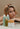 Woman with long blonde hair beside the Mimane Glow shampoo, conditioner, hair oil, and hair mask