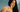 Woman with long straight black hair holding Mimane Glow hair oil