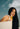 Woman with long straight black hair holding Mimane Glow hair oil