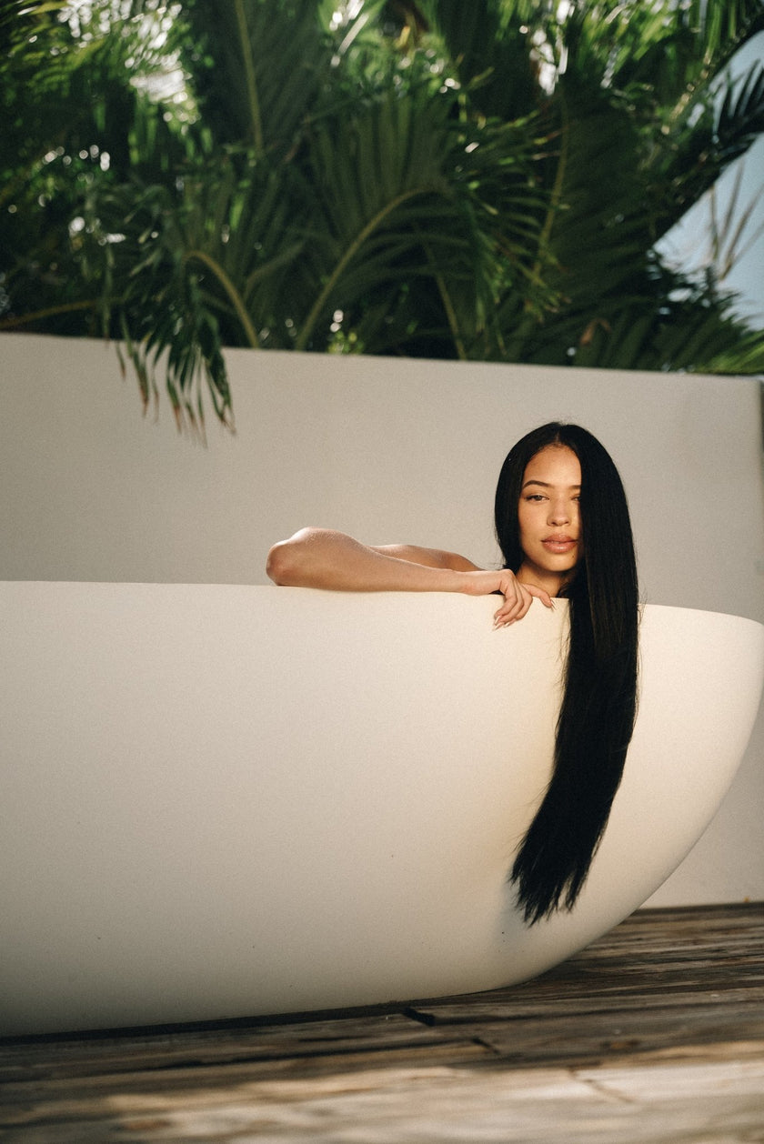 Woman in a white bathtub with Mimane Glow hair care